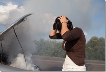 Woman looking at smoking car engine